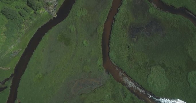 High top-down aerial moving over river tributaries, marshy grasslands and glens of Loch Dochart in the Scottish Highlands