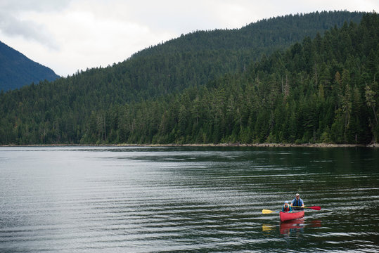 Man and Child Paddling a Canoe on a Mountain Lake