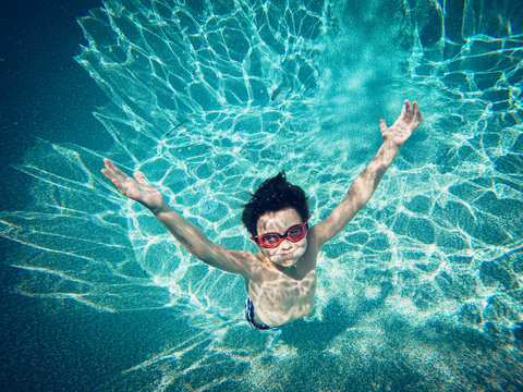 Underwater image of young boy floating in a swimming pool.