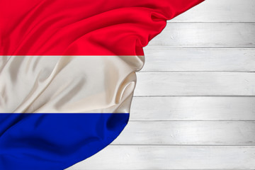 horizontal colored national flag of modern state of the Netherlands, beautiful silk, white wood background, concept of tourism, economy, politics, emigration, independence day, copy space, template