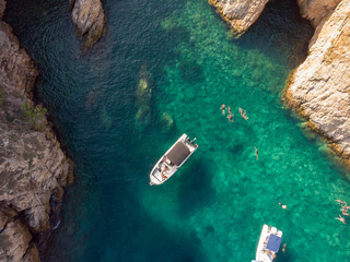 Aerial view of people swimming off boats in a paradise lagoon.