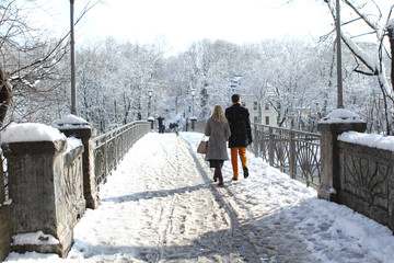 man and woman walk along the bridge together among the cold white landscape of the city of Munich...