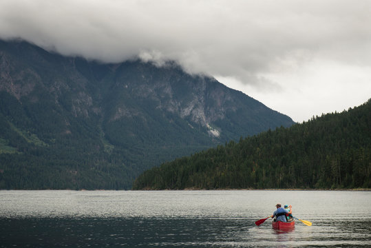 Man and Child Paddling a Red Canoe on a Mountain Lake