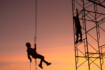 Silhouette; construction worker Climbing scaffolding In order to go up to check the work site