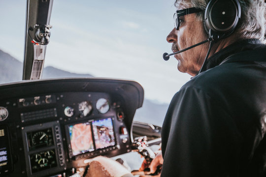 Baby boomer aged man enjoys flying helicopter in the mountains.