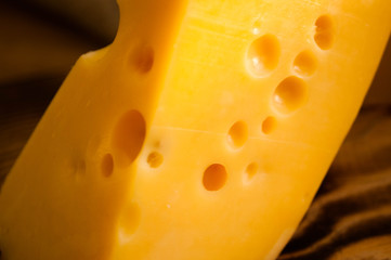 Cheese with holes. Tasty cheese pieces on wooden desk 