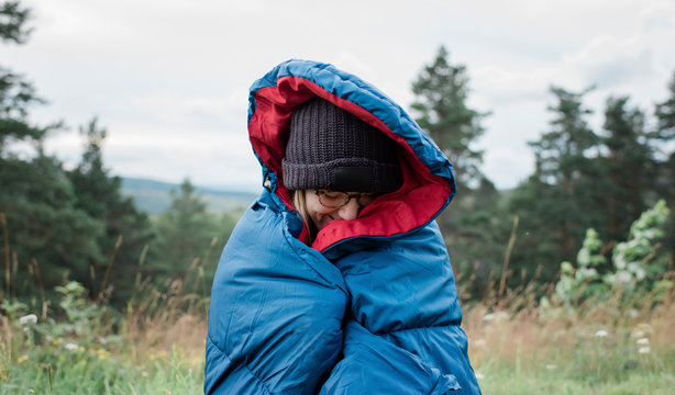 portrait of a woman wrapped up in a sleeping bag wild camping outdoors