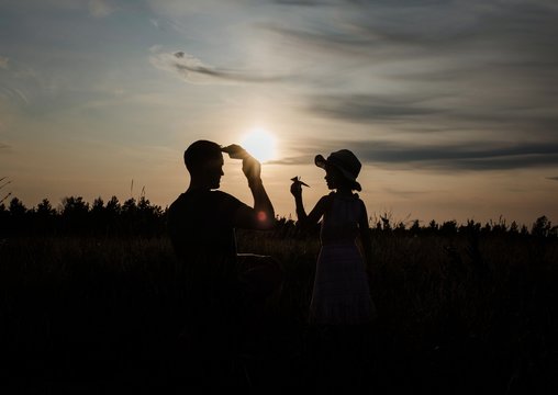 silhouette of father and daughter playing outside with paper aeroplane