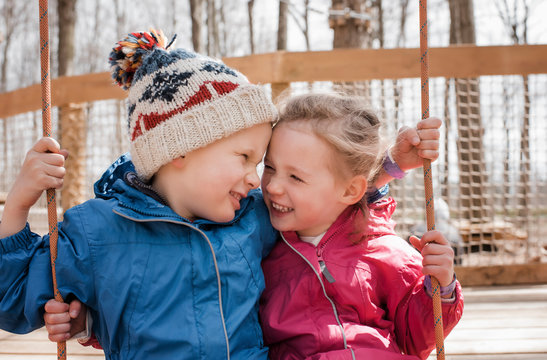 girl and boy on a swing together playing and laughing outside