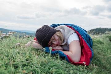 woman sleeping in her sleeping bag on a mountain outside