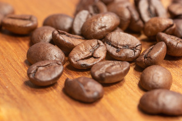 Coffee beans laying on a wooden cutting board in harsh light close up 2