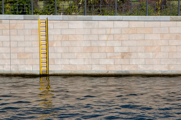 Yellow ladder on a concrete block wall on the edge of the River