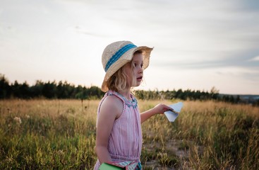 portrait of a young girl playing with paper planes in a meadow