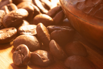 Coffee beans on a wooden cutting board laying around a copper coffee brewer in harsh light. Hazy picture vintage feeling. Lazy Sunday morning