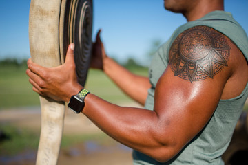 A strong man flexes his bicep and holds a fraying piece of firehose