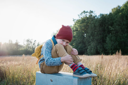young school boy sitting on a post whilst walking home from school