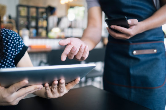 Young waiter using a digital tablet to show the menu to a custom
