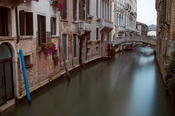 Long exposure of a Venice Canal lined with colorful houses and bridges in the background