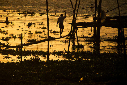 Fisherman balancing on Chinese Fishing Nets structure