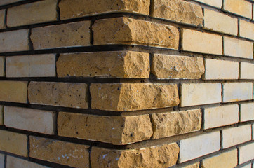 The corner of the building is made of yellow silicate brick in rustic style. There are finishing bricks with a chipped edge. Background. Texture.