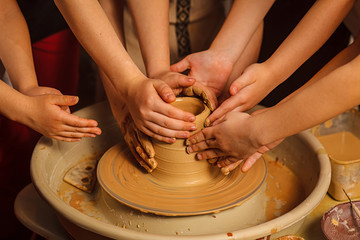 A close-up of the hand of a male potter who teaches his pupil, a child of the art of making a pot or a vase of clay. People working on potters.