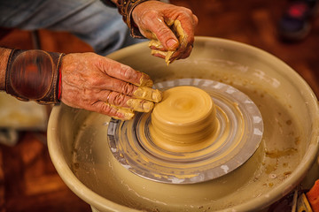 The master forms a clay cup on a potter's wheel. A potter's hands preparing a clay pot. Close-up.