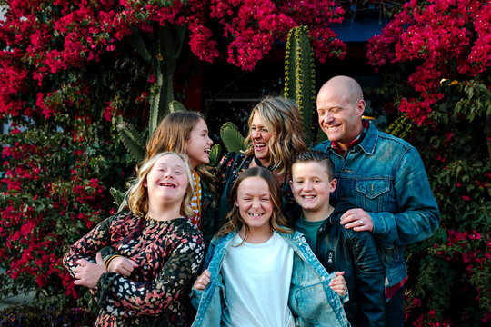 Laughing family in front of red flowering bushes