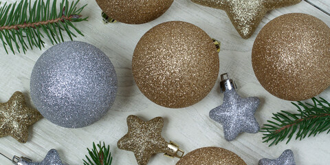 silver and golden Christmas decorations in the shape of balls and stars lie on a white aged wooden surface