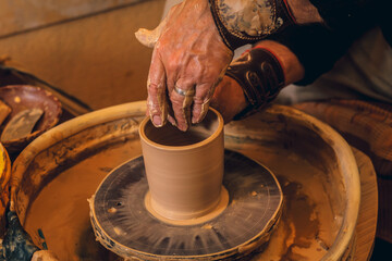 The master forms a clay cup on a potter's wheel. A potter's hands preparing a clay pot. Close-up.
