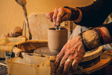 The master forms a clay cup on a potter's wheel. A potter's hands preparing a clay pot. Close-up.