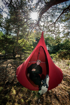 Senior man relaxing in hanging tent
