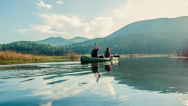 A beautiful view of a couple on a canoe ride. They're enjoying themselves. The day is nice.