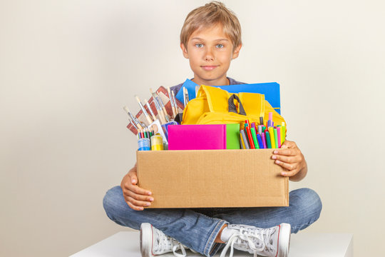 Donation concept. Kid holding donate box with books, pencils and school supplies