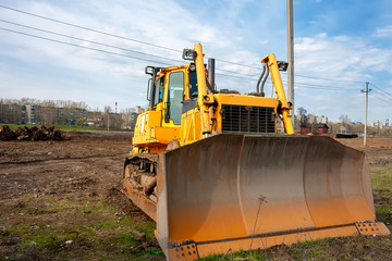 A large orange bulldozer stands at a construction site.