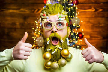 Fashion portrait of handsome man indoors with Christmas tree. New year concept. Sexy Santa man...