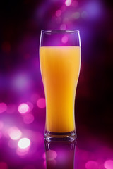 Glass of orange juice over pink defocused lights