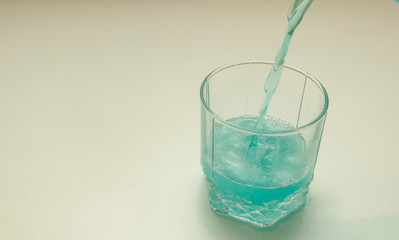 Blue ale with bubbles and ice. Pouring the drink in the glass. Bright drink with white background.  Bubbles.