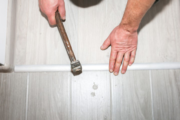 Installation of threshold indoors. Renovation works in the flat. Man with a hammer.