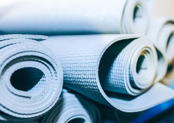 Grey yoga and pilates mats are lying in the fitness centre. Sports equipment in the gym. Exercises for fit body.
