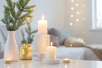 Christmas decorations with burning candles in white interior