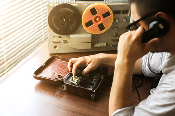 Special agent holds field telephone . Officer wiretapping   on the reel tape recorder. FBI spying conversations.