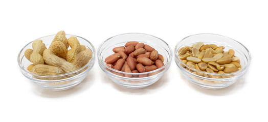 arachidi con guscio, pelle e senza all'interno di una ciotola di vetro su uno sfondo bianco