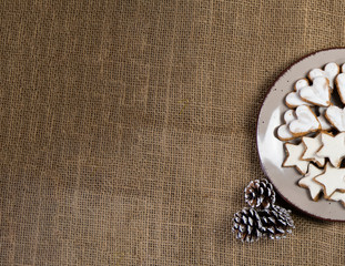 Cinnamon star cookies on a plate surrounded by Golden Christmas ornaments on a  Sackcloth tablecloth flat or top view 