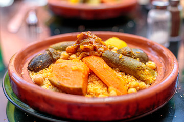 High angle closeup shot of couscous in a clay plate on blurred background