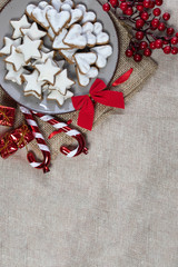 Cinnamon star cookies on a plate surrounded by Golden Christmas ornaments on a  Sackcloth tablecloth flat or top view 