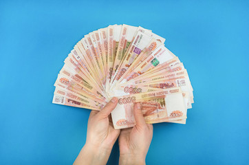 Girl holding money in her hands on a blue background.