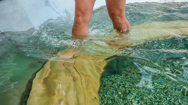 A guy is in a pool and he is walking around in a circle.