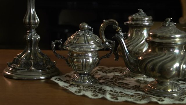 Slowly overview of a silverware tea set near two vintage candle holders FDV