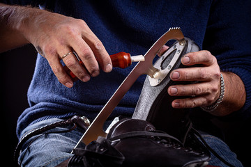 Man's hand and handheld skate sharpening tool with ice skate  - obrazy, fototapety, plakaty