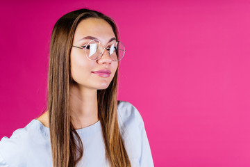 the girl in glasses for vision smiles slightly at the camera. fuchsia background